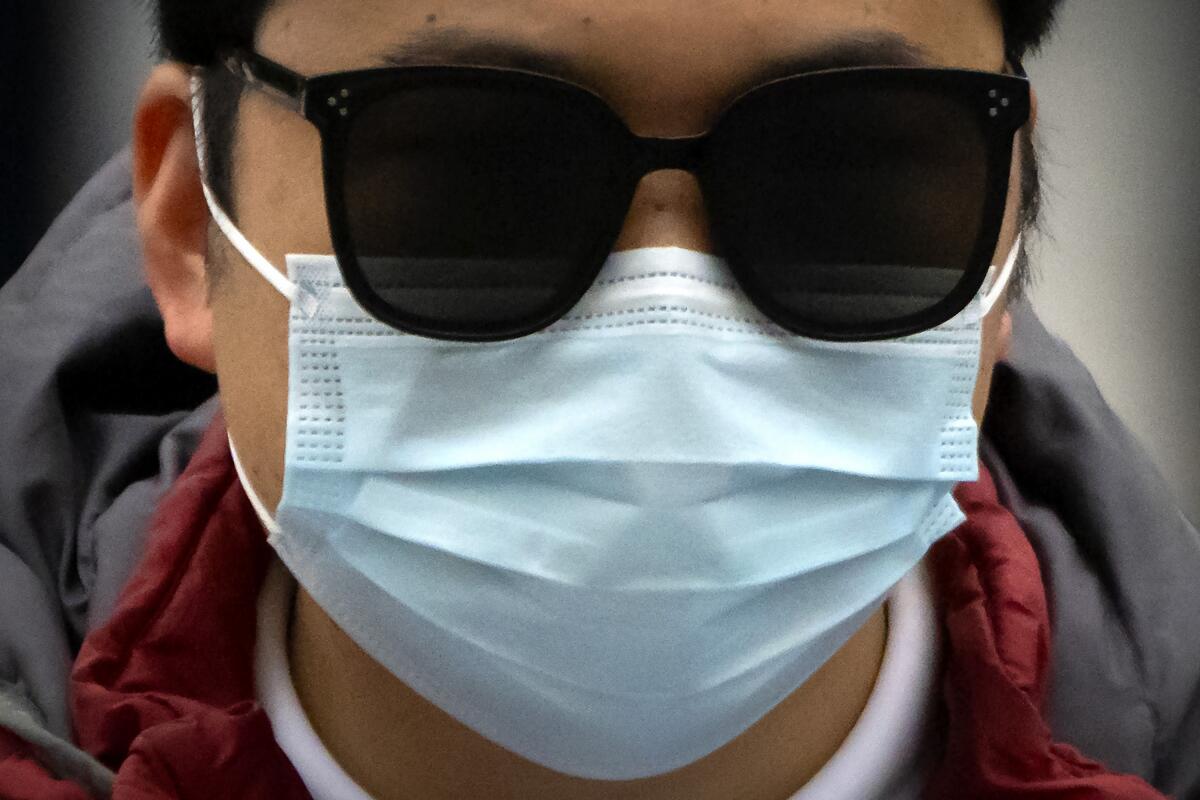A commuter wearing a face mask and sunglasses.