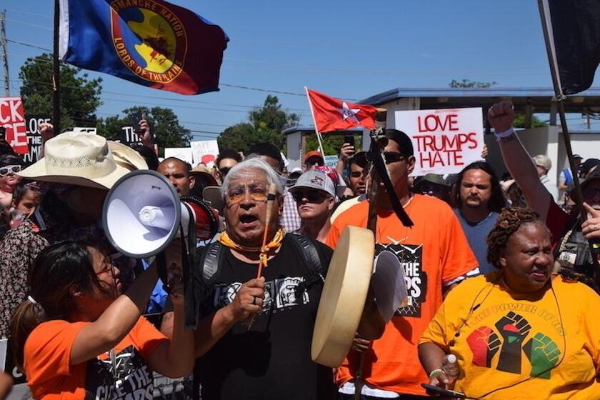 El doctor Cornel Pewewardy toca un tambor y encabeza una protesta mientras marchan por la avenida Nortwest Osmun y Sheridan Road hasta los accesos de Fort Sill, en protesta contra los planes del gobierno de Estados Unidos de mantener detenidos a menores migrantes en esa instalación, en Lawton, Oklahoma.