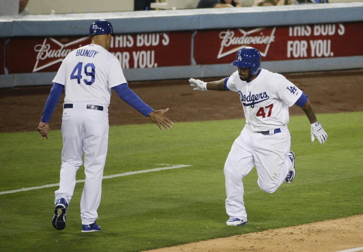 El jugador de los Dodgers, Howie Kendrick, celebra su jonrón con el entrenador de tercera base.