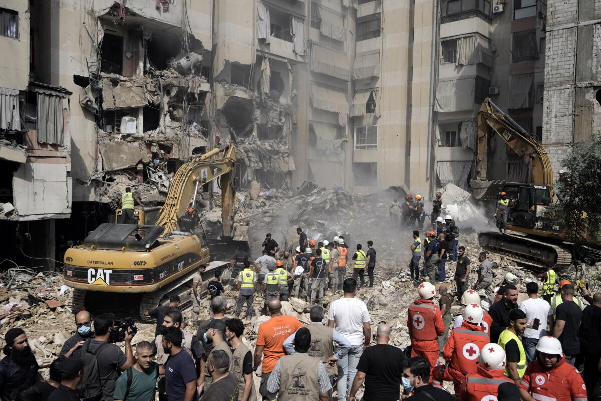 Emergency workers use excavators to clear the rubble at the site of Friday's Israeli strike in Beirut's southern suburbs.