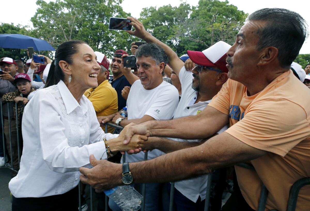 Mexican presidential candidate Claudia Sheinbaum shakes hands with a crowd of supporters. 