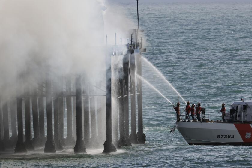 OCEANSIDE, CA - APRIL 25, 2024: The crew of a U.S. Coast Guard boat sprays water as firefighters fight a fire burning at the end of the Oceanside Municipal Pier in Oceanside on Thursday, April 25, 2024.