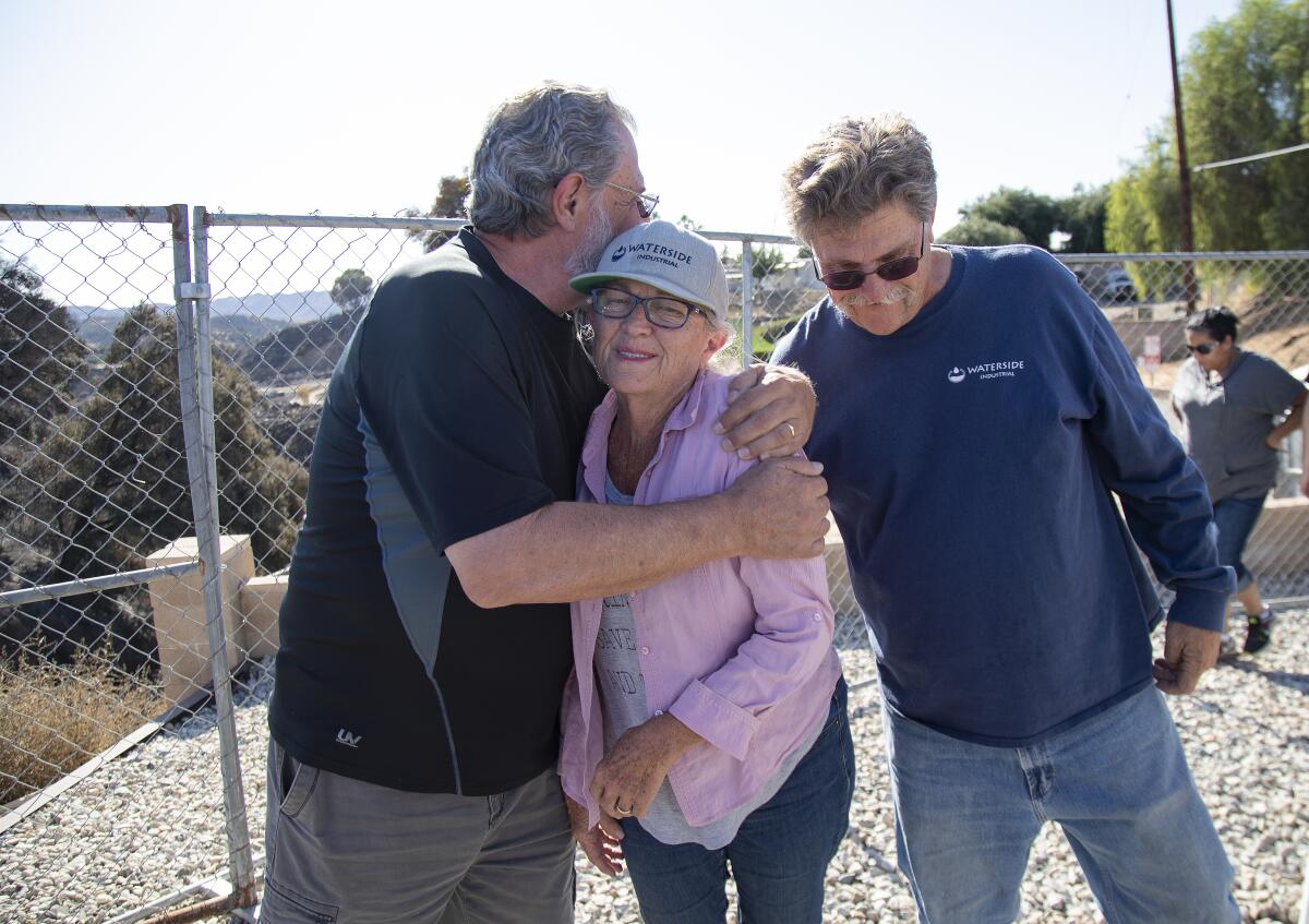 Brothers Doug Turner,68, left, and Don Turner,62, embrace their sister Judy Dorius, 70, outside the Villa Calimesa Mobile Home Park where their mother Lois Arvickson, 89, died during the Sandalwood Fire in Calimesa, California.