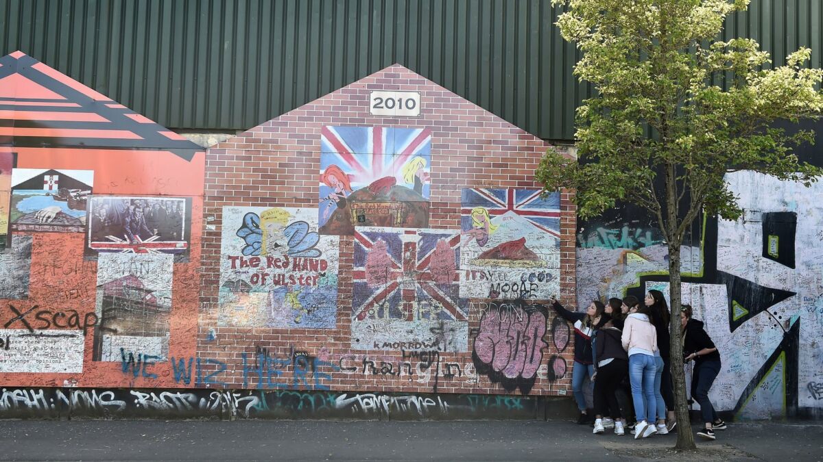 Tourists take photographs beside the peace wall that separates the Catholic and Protestant communities in Belfast.