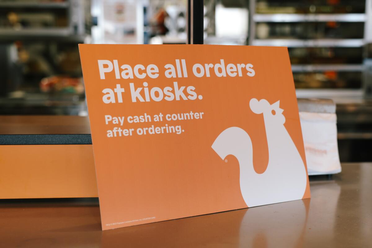 Signage alerts customers to order from a kiosk at Popeyes Louisiana Kitchen in Los Angeles.