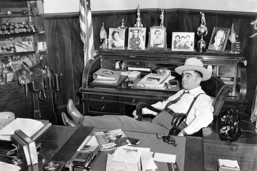 1943 file photo of Sheriff Eugene Biscailuz sitting in his office with the mementos of 10 years of service.