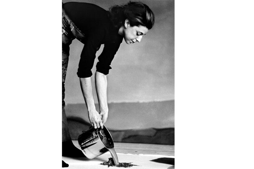Helen Frankenthaler tips a can of paint onto a canvas on the floor.