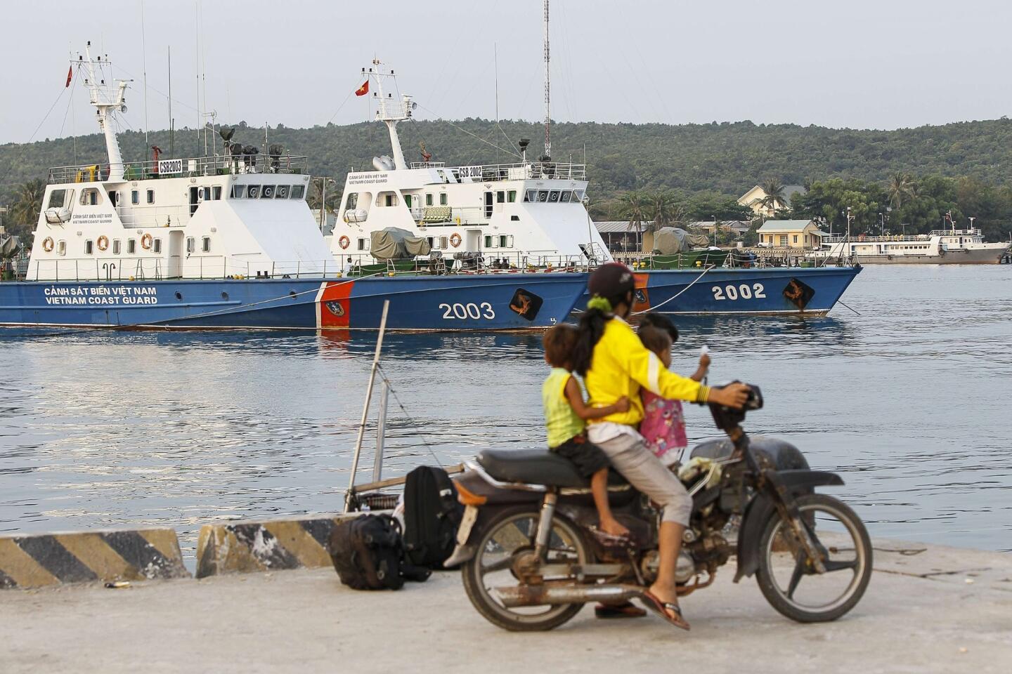 Residents look at ships anchored at a local naval base at Phu Quoc island, in the waters of southern Vietnam, where a Malaysian Airlines jet was presumed lost.