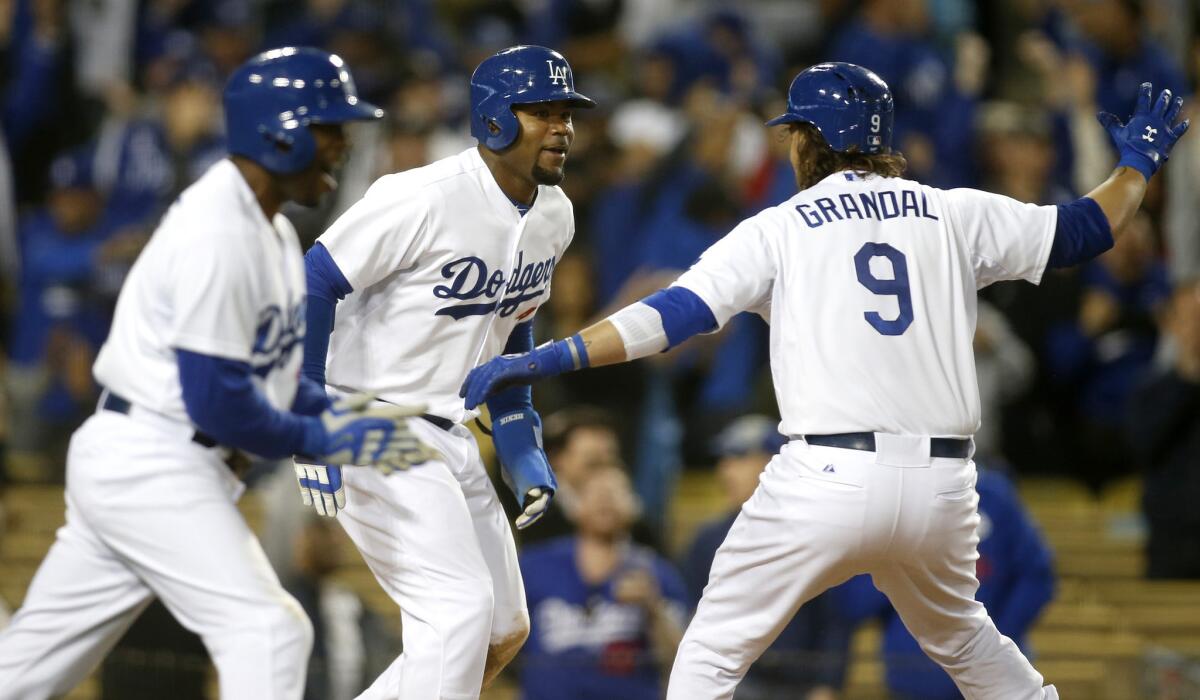 Dodgers catcher Yasmani Grandal (9) celebrates with Carl Crawford, center, and Jimmy Rollins after Crawford scored the winning run on a hit by Howie Kendrick on Tuesday night.