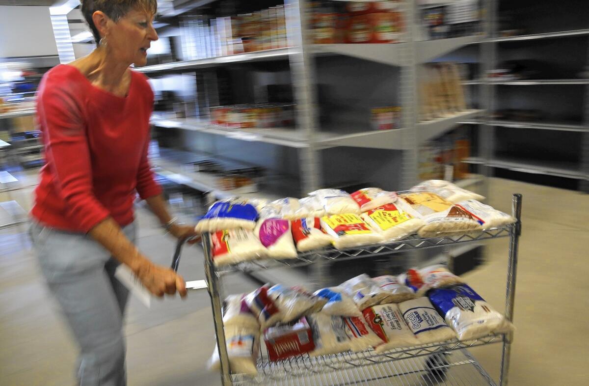 Volunteer Lani Orr pushes a cart of rice at the Families Forward pantry in Irvine in 2013. Orange County has a public-private partnership for reducing food waste from restaurants and other businesses.