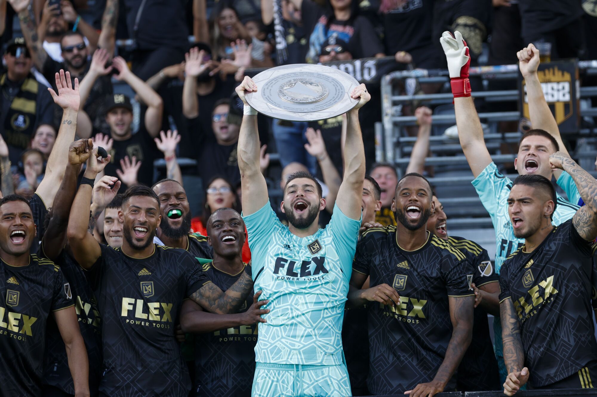 LAFC kalecisi Maxime Crepeau, Taraftar Kalkanı kupasını kaldırıyor ve takım arkadaşlarıyla kutlama yaparken gülümsüyor.