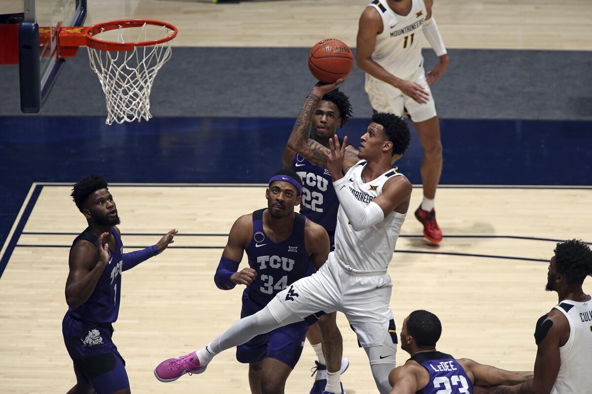 West Virginia forward Jalen Bridges (2) shoots while defended by TCU forward Kevin Easley (34) and guard RJ Nembhard (22) during the first half of an NCAA college basketball game Thursday, March 4, 2021, in Morgantown, W.Va. (AP Photo/Kathleen Batten)