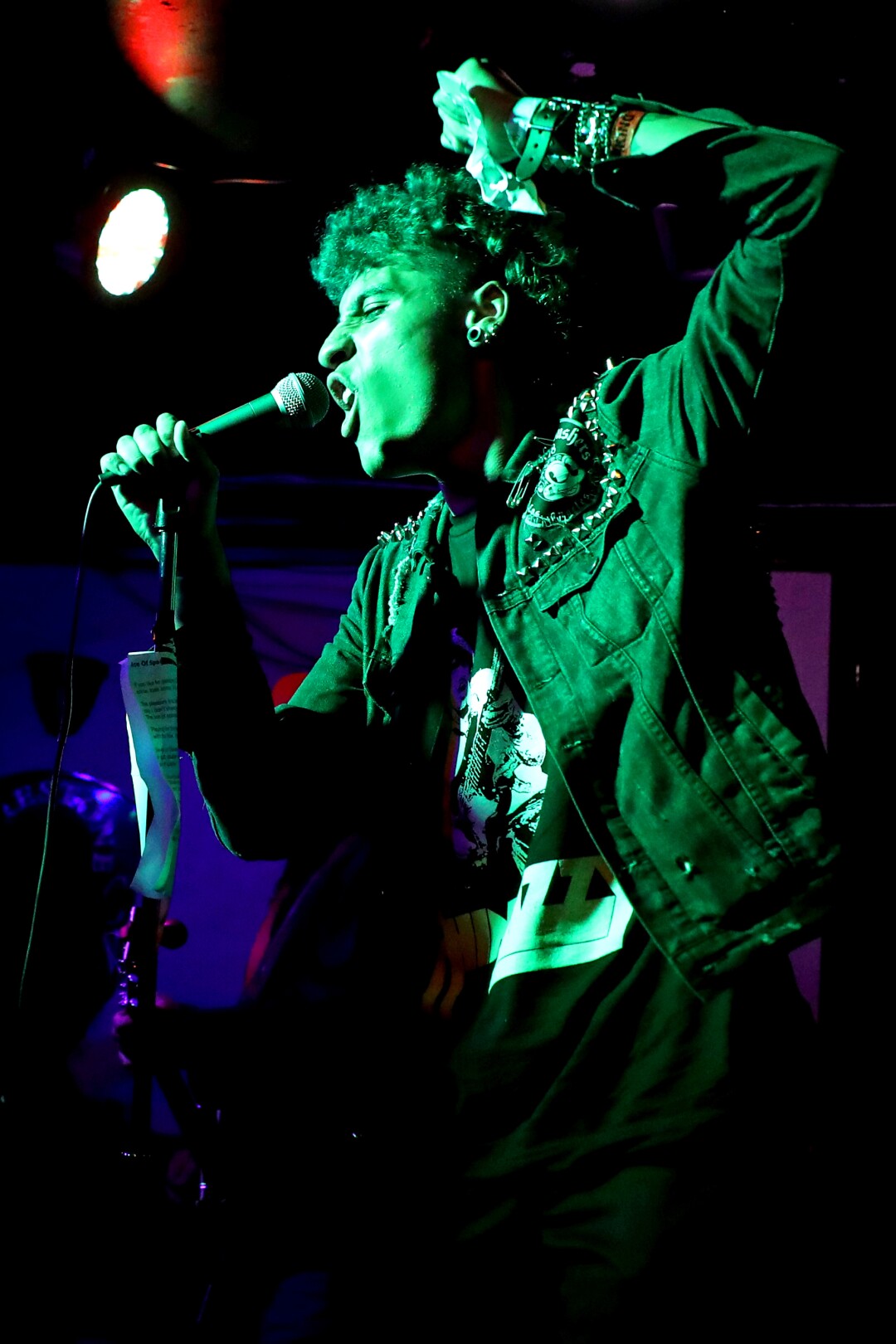 A man sings into a green light on a stage