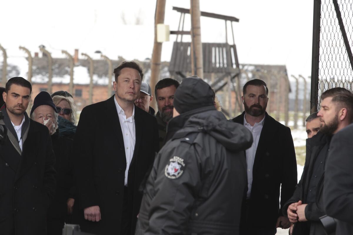 Elon Musk with a crowd of people at the site of the Auschwitz-Birkenau Nazi death camp in Oswiecim, Poland