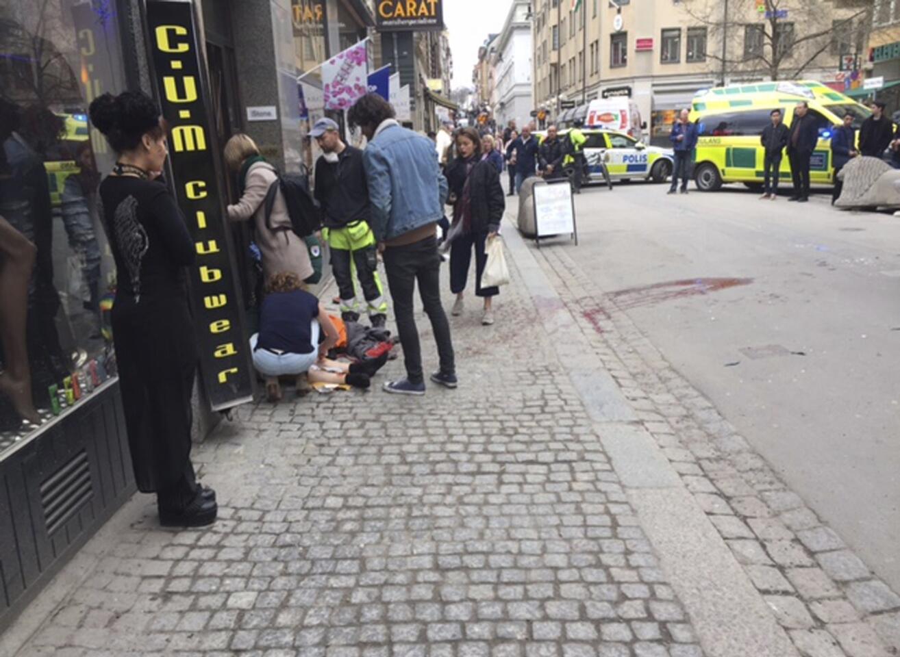 Miembros de los servicios de emergencia atienden a uno de los heridos en la zona donde un camión que atropelló a varias personas y se estrelló contra una tienda de la calle comercial de Drottninggatan en el centro de Estocolmo, Suecia.