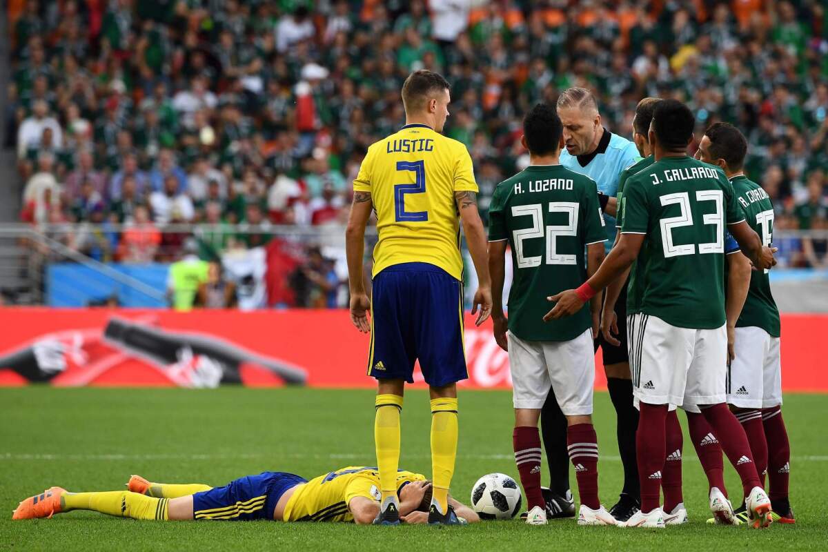 Referee Nestor Pitana presents Mexico's Jesus Gallardo with a yellow card during a June 27 match against Sweden.