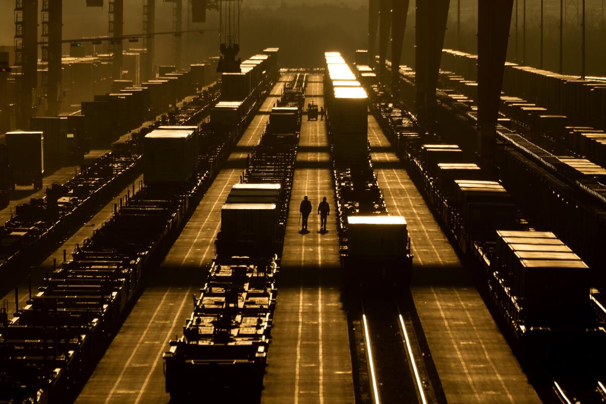 Workers walk among shipping containers at a BNSF intermodal terminal. 
