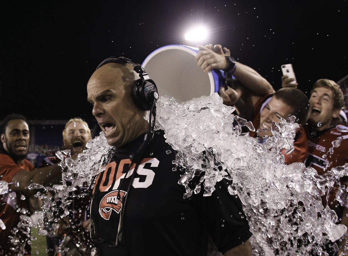 Western Kentucky players douse interim Coach Nick Holt after defeating Memphis in the Boca Raton Bowl game.