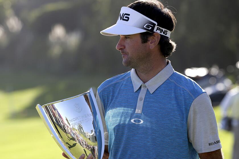 Bubba Watson cradles the winner's trophy on the 18th green after rallying for a victory in the Northern Trust Open at Riviera Country Club on Sunday.