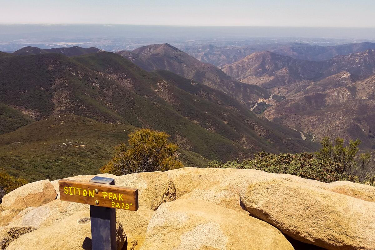 "Sitton Peak" sign on a rock with view of dry mountains 