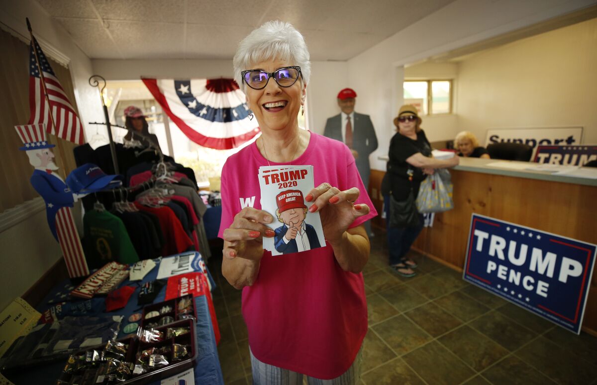 Volunteer Mary Jane Loya holds up Trump 2020 gear at Kings County Republican headquarters in Hanford, Calif.