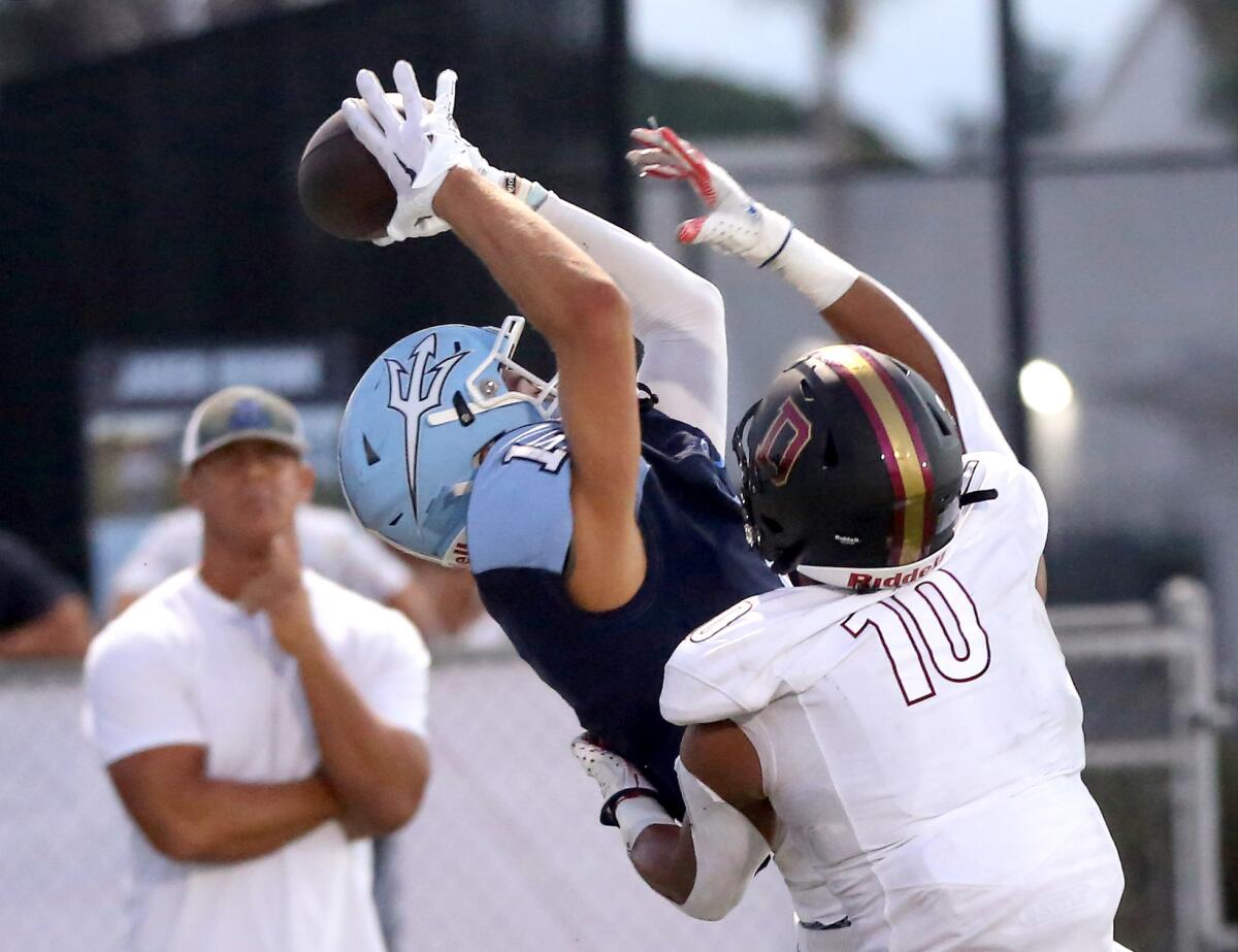 Corona del Mar's Cooper Hoch (1) reels in a touchdown during a football game against Downey in Newport Beach.