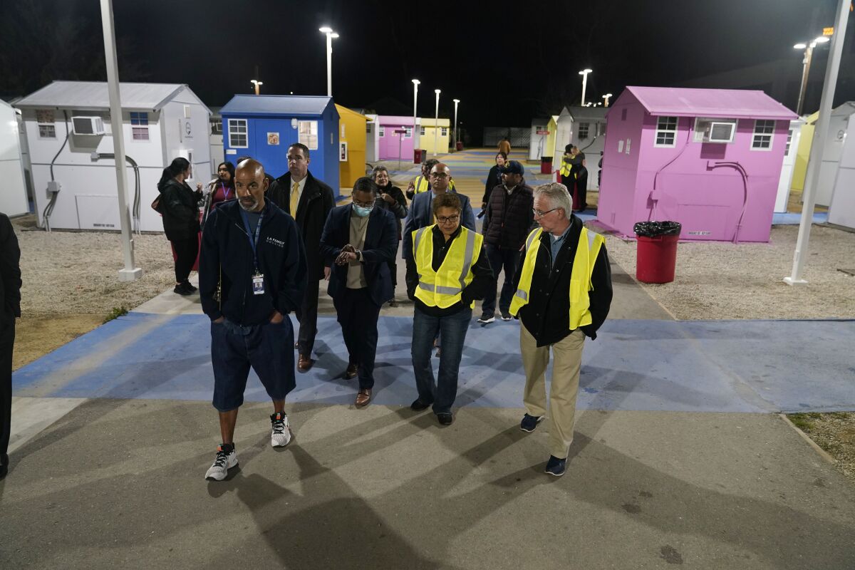 Mayor Karen Bass, center in yellow, tours a tiny homes community for the homeless alongside city councilman Paul Krekorian, right, during the annual homeless count in the North Hollywood section of Los Angeles Tuesday, Jan. 24, 2023. Thousands of clipboard-toting volunteers with the LA Homeless Services Authority fanned out across the county Tuesday night for the effort's main component, the unsheltered street tally. (AP Photo/Marcio Jose Sanchez)