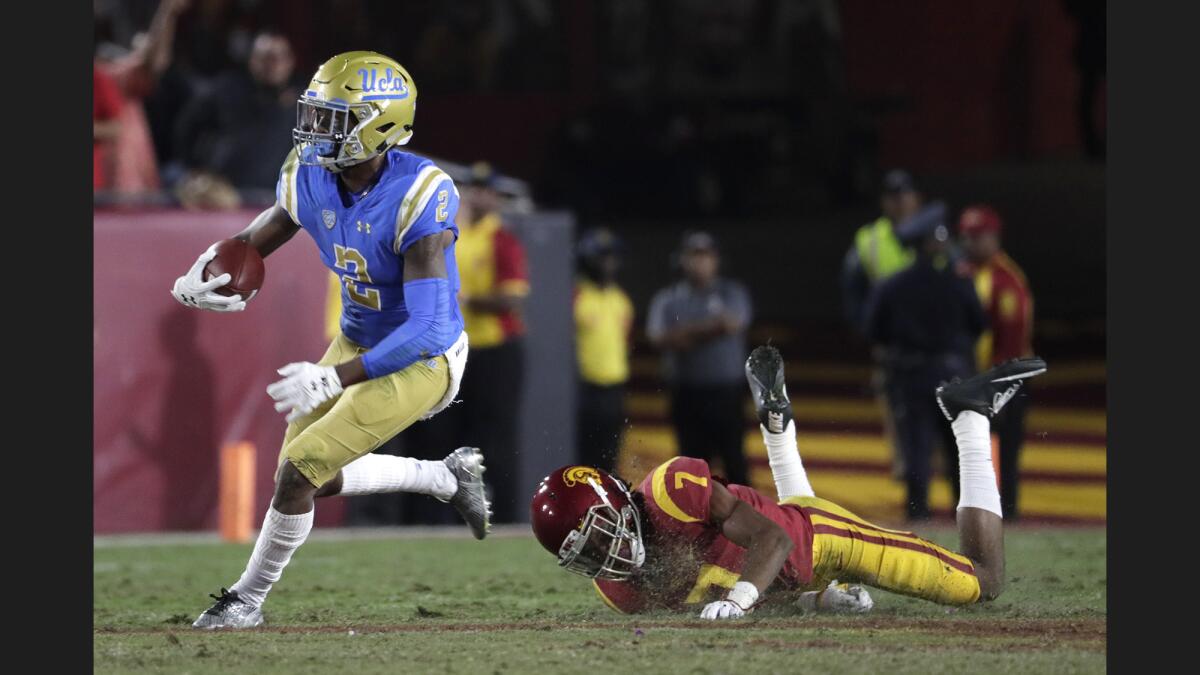 UCLA receiver Jordan Lasley, left, eludes USC safety Marvell Tell III at the Coliseum on Saturday.