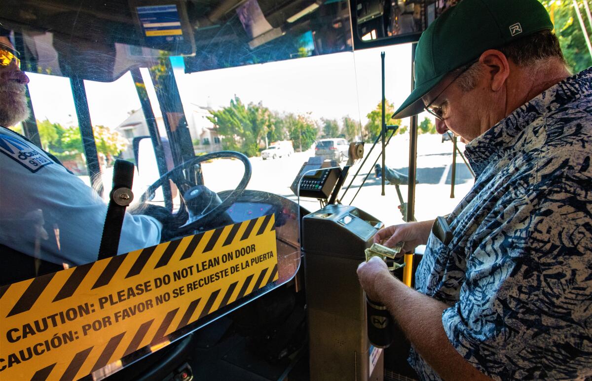 Costa Mesa Mayor John Stephens pays for bus fare during an Oct. 6 in-town trip with Councilwoman Arlis Reynolds.