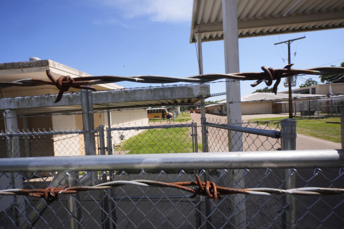 School buses are seen beyond a barbed wire fence at Ferriday High School in Ferriday, La.