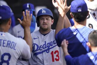 Los Angeles Dodgers' Max Muncy celebrates in the dugout after scoring on a wild pitch.