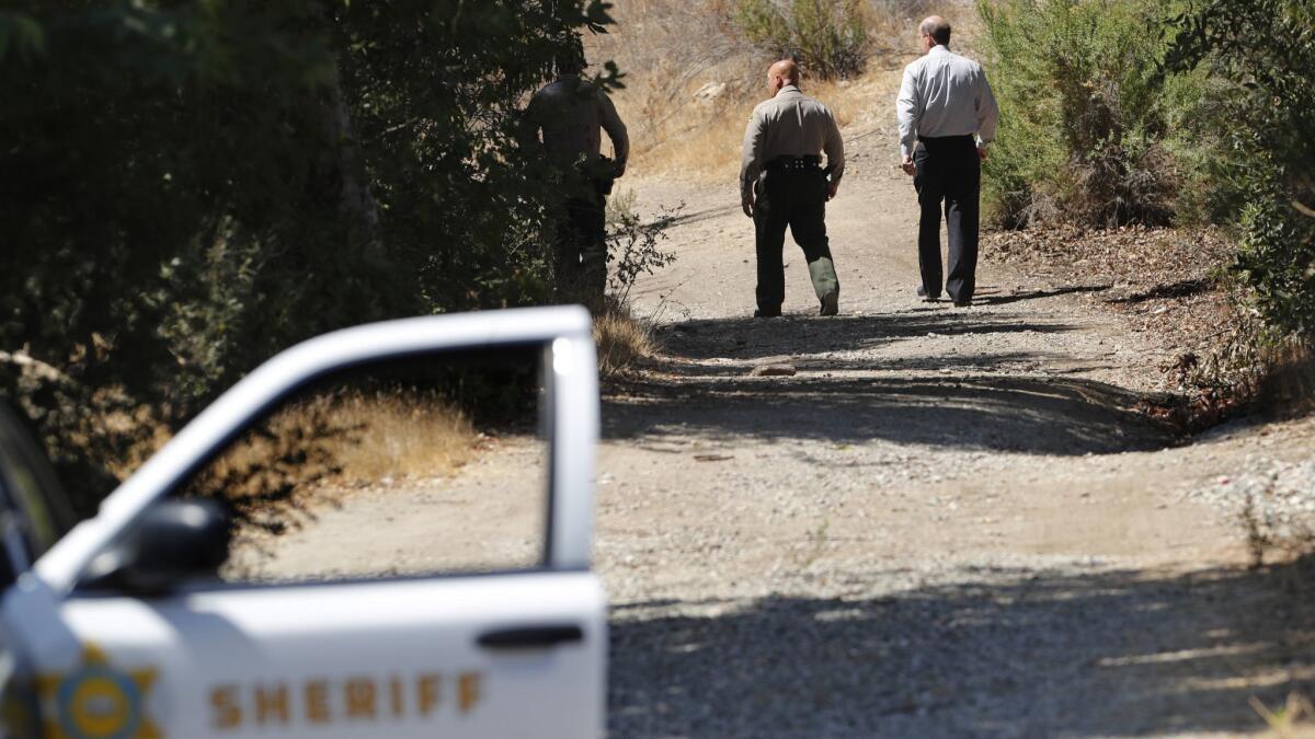 Captain Josh Thai, center, of the Los Angeles County Sheriff's Dept., and Dr. Gary Lysik, right, City Manager for the City of Calabasas make their way to the scene where several human bones were found off of the Juan Bautista de Anza East Trailhead in Calabasas.