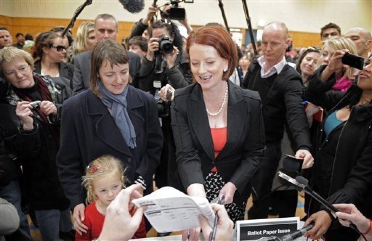 Australian Prime Minister Julia Gillard, center right, of the Federal Labor Party receives her ballot papers before voting at the Seabrook Primary School in Melbourne, Australia, Saturday, Aug. 21, 2010. Standing on her left are Health Minister Nicola Roxon and her daughter Rebecca. (AP Photo/Mark Graham)