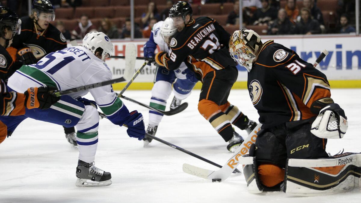 Ducks goalie Frederik Andersen stops a shot in front of Vancouver Canucks forward Derek Dorsett, left, during the first period of the Ducks' 2-1 overtime win Sunday.