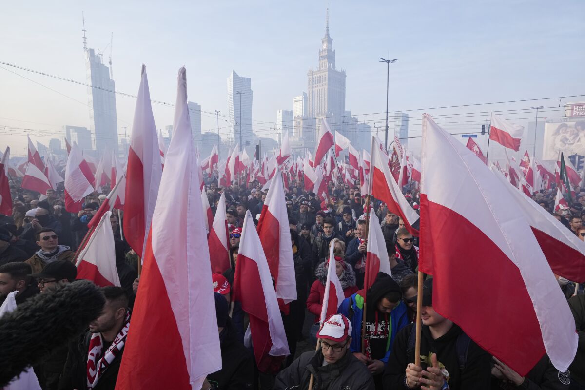 People hold Polish flags during the annual Independence Day march which because of their participation turned violent in recent years, in Warsaw, Poland, on Thursday, November 11, 2021. Warsaw mayor and courts banned this year's event due to its history of violence, but the right-wing ruling authorities defied the ban and gave the march state event status to allow it to go ahead.. (AP Photo/Czarek Sokolowski)