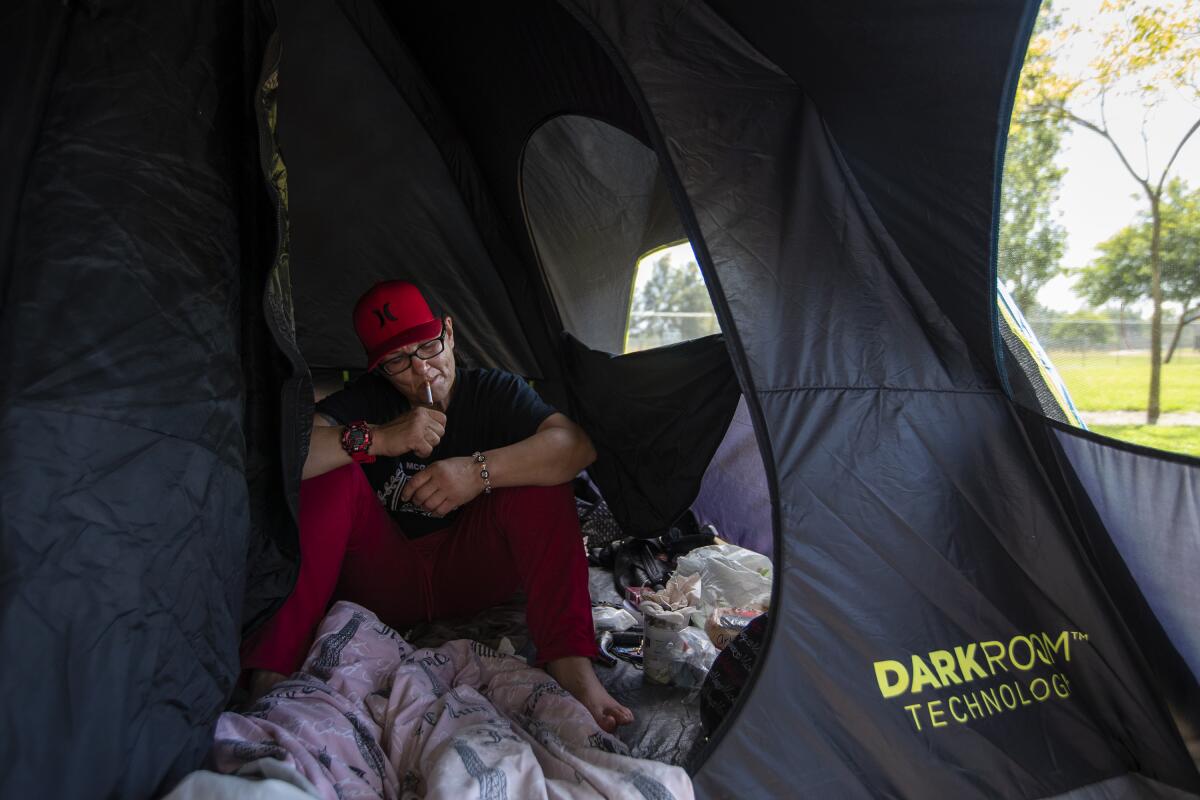 MJ (chose not to give her last name) lights a cigarette in her tent near the Fountain Valley Sports Park on Thursday.