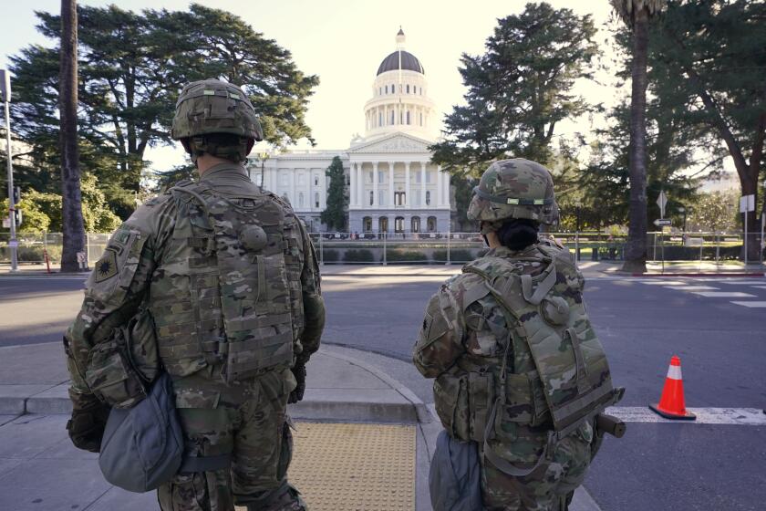 Members of the California National Guard walk past the California state Capitol in Sacramento, Calif., Wednesday, Jan. 20, 2021. A temporary 6-foot high chain link fence surrounds the Capitol and California Gov. Gavin Newsom mobilized the National guard last week over concerns that protests around the inauguration of President Joe Biden could turn violent and destructive. (AP Photo/Rich Pedroncelli)