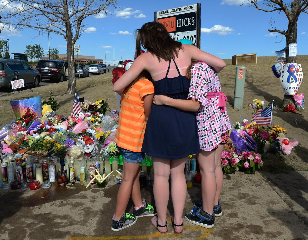 Sisters hug at a makeshift memorial across the street from the Century 16 movie theater the day after a gunman killed 12 people and injured 59 in Aurora, Colo.