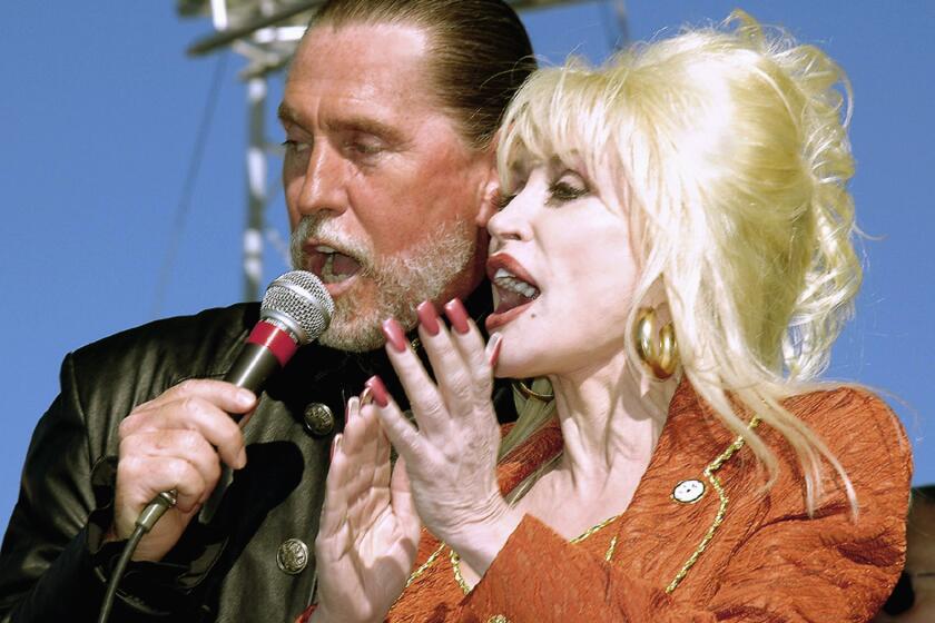 FILE - Dolly Parton shares the microphone with her brother Randy Parton during a celebration marking the groundbreaking for the Carolina Crossroads Music & Entertainment Center in Roanoke Rapids, N.C. on Nov. 11, 2005. Parton said her brother and singing partner Randy Parton has died of cancer. She said in a statement released Thursday that her brother sang, played guitar and bass in her band, as well hosting his own show at her theme park, Dollywood, in East Tennessee. He was 67. (Todd Wetherington/The Daily Herald via AP)
