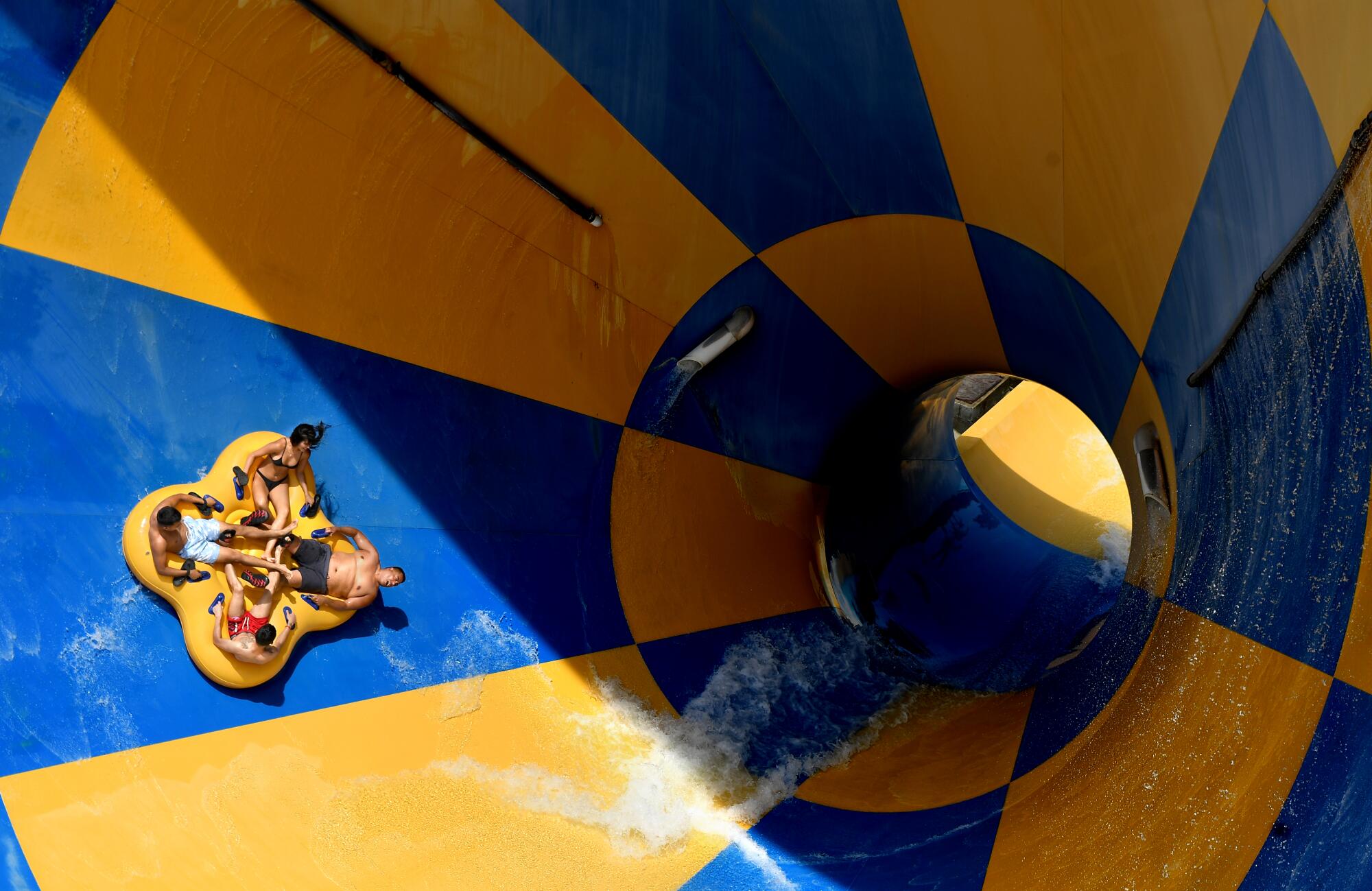 Four people on an innertube go down a waterslide