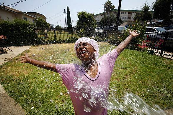 COOLING OFF: On a hot summer day, Sade Jones, 6, plays in the refreshing spray of a garden hose in her cousin's front yard near West 126th Street and South Figueroa Street in South Los Angeles.