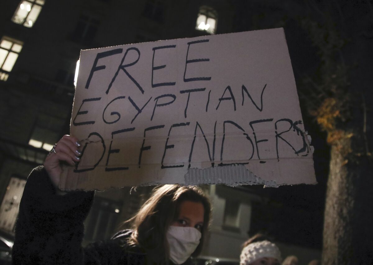A woman holds a placard as she stages a protest against the Egyptian President Abdel-Fattah el-Sissi by the National Assembly in Paris, Tuesday, Dec. 8, 2020. French President Emmanuel Macron acknowledged Monday "disagreements" with Egyptian President Abdel-Fattah el-Sissi over human rights, but said it will not prevent France from reaching economic and defense deals with the North African country, which has seen the heaviest crackdown on dissent in its modern history. (AP Photo/Michel Euler)