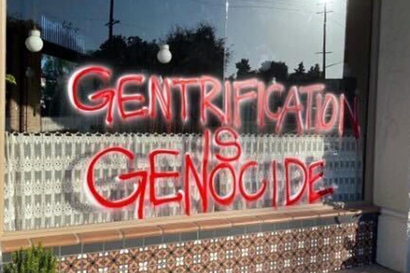 "Gentrification Is Genocide" graffiti spray-painted on windows 