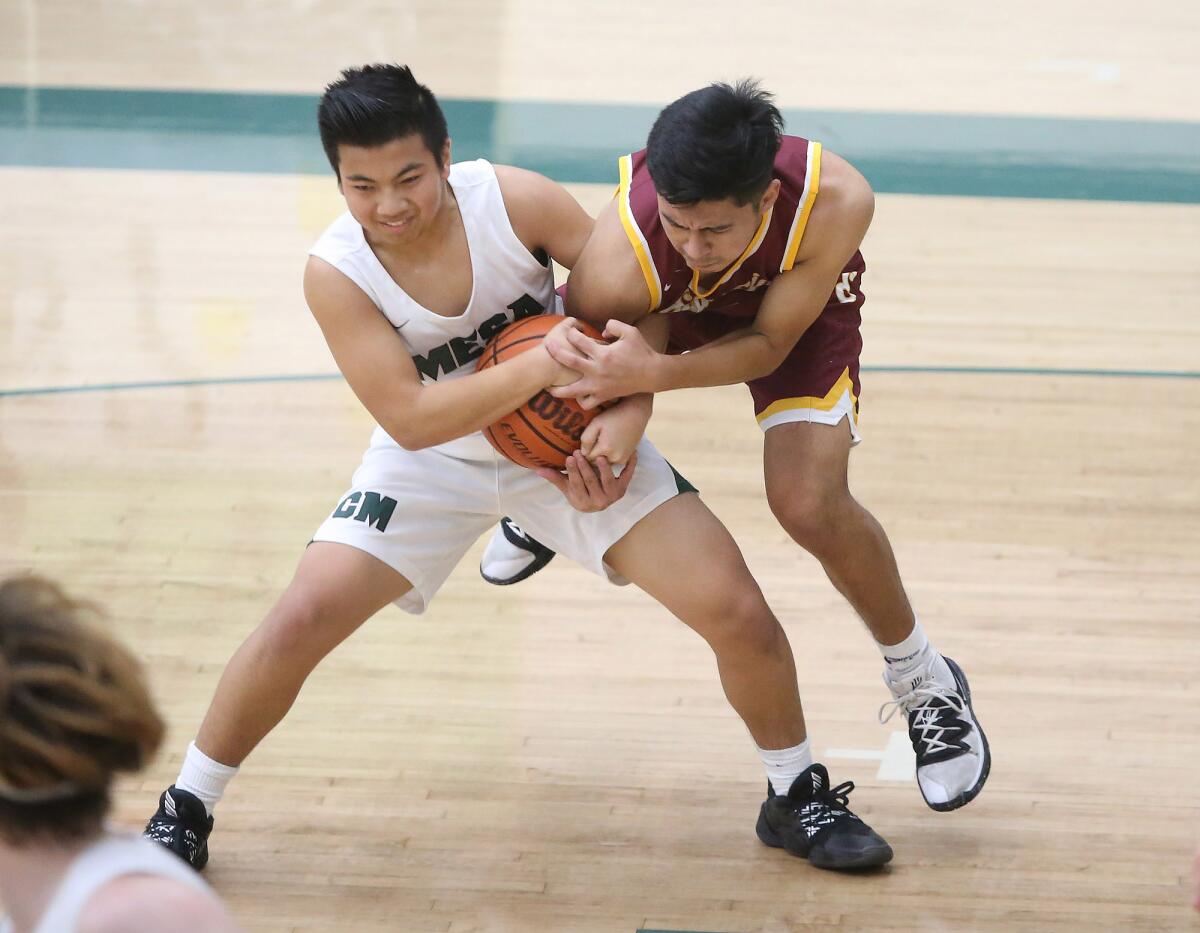Costa Mesa's Christian Dasca, left, and Estancia's Larry Andres wrestle for a loose ball during an Orange Coast League game on Wednesday.