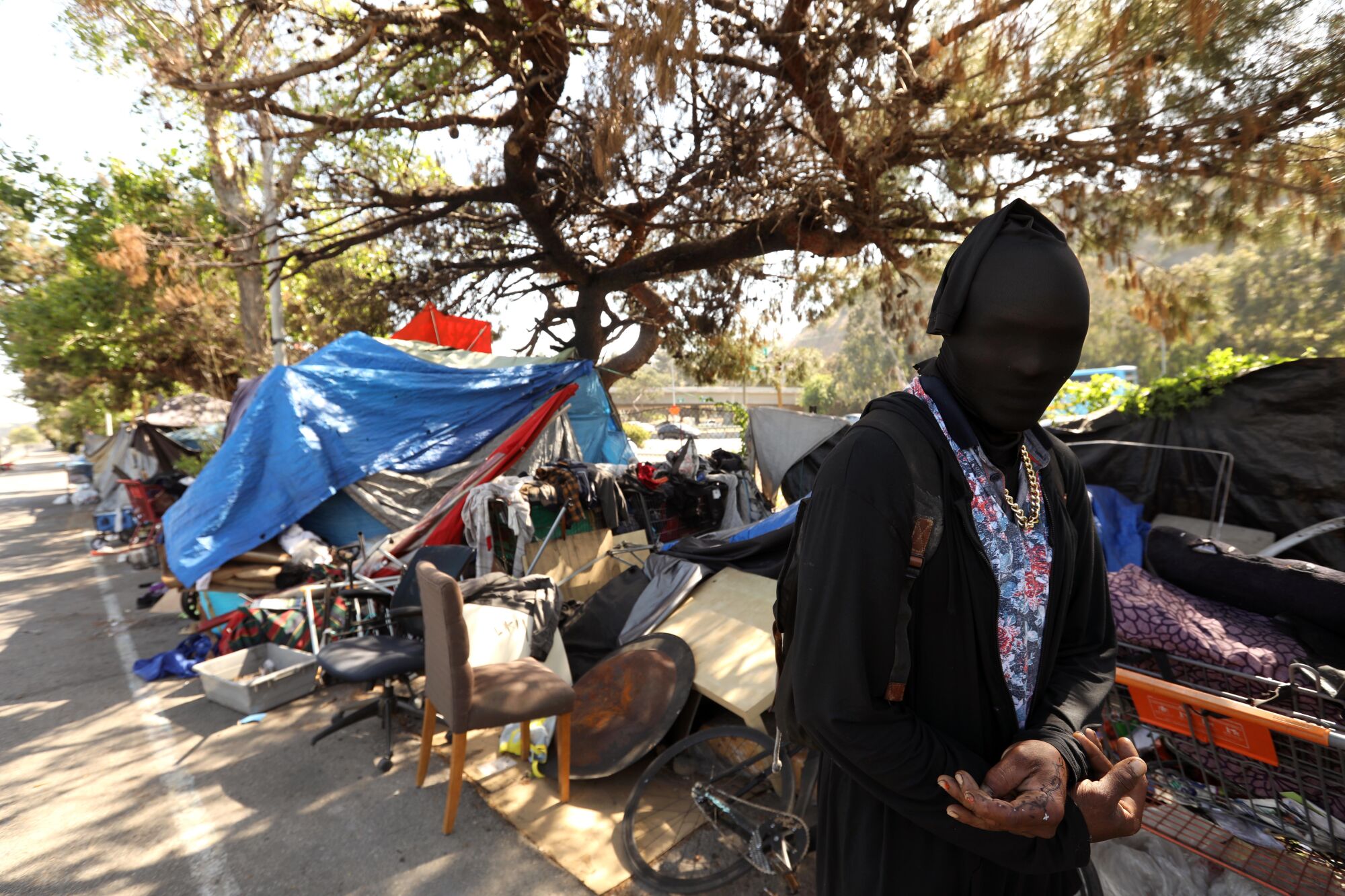 A man stands outside a homeless encampment 