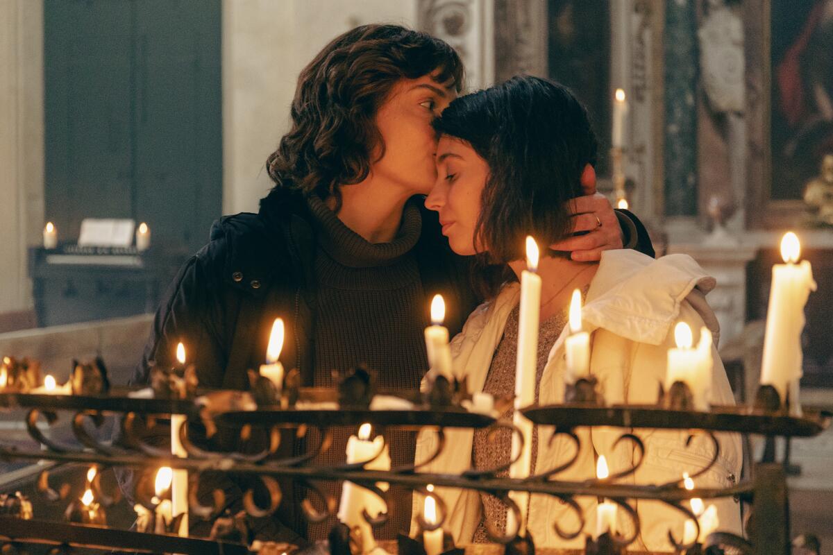 One woman kisses another on a forehead in church.