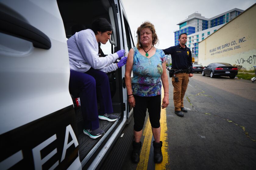 Registered Nurser Andrea Huerta injects a homeless woman named Deanna the Hepatitis A vaccine during street outreach work with the San Diego Police Homeless Outreach Team on Wednesday, May 24, 2023 in San Diego, CA.