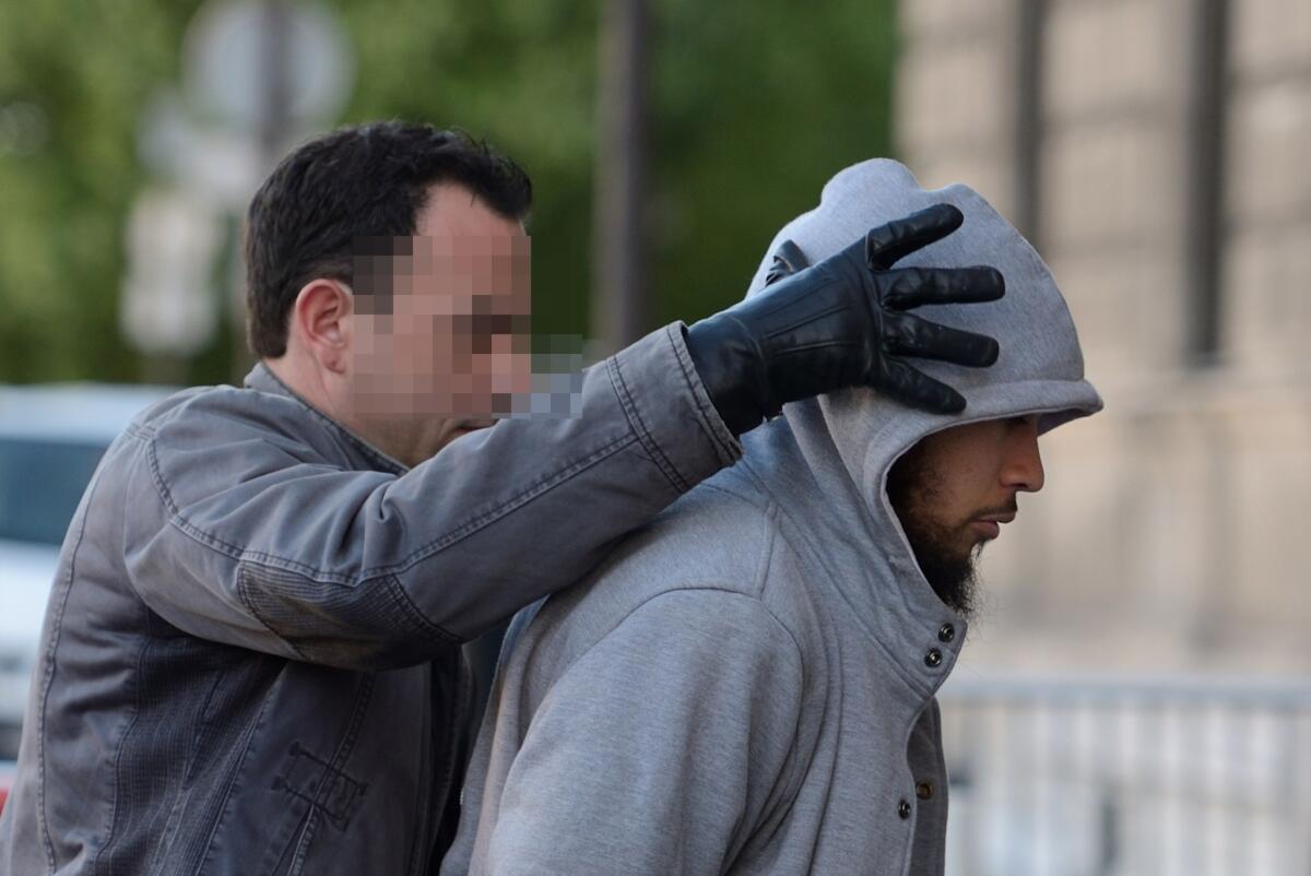 The suspected perpetrator, right, in the stabbing of a French soldier is escorted by a police officer as he arrives at police headquarters in Paris on Wednesday.