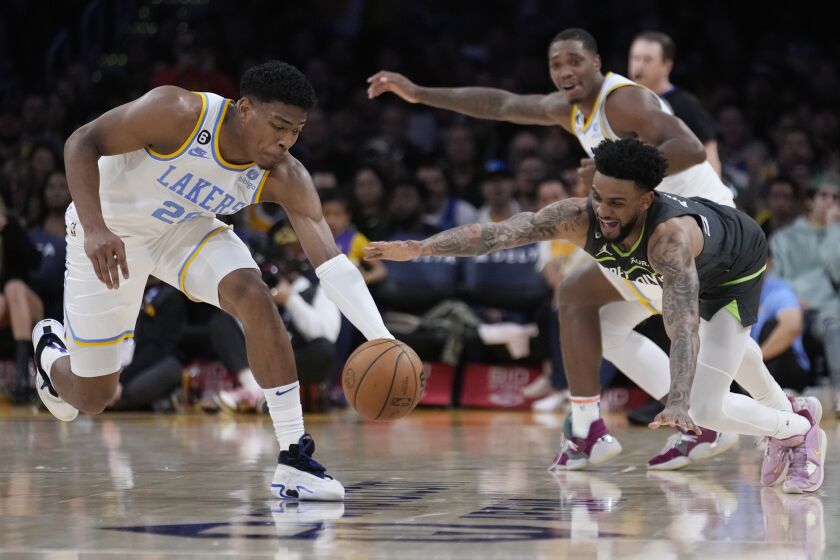 Los Angeles Lakers' Rui Hachimura, left, recovers a loose ball next to Minnesota Timberwolves.