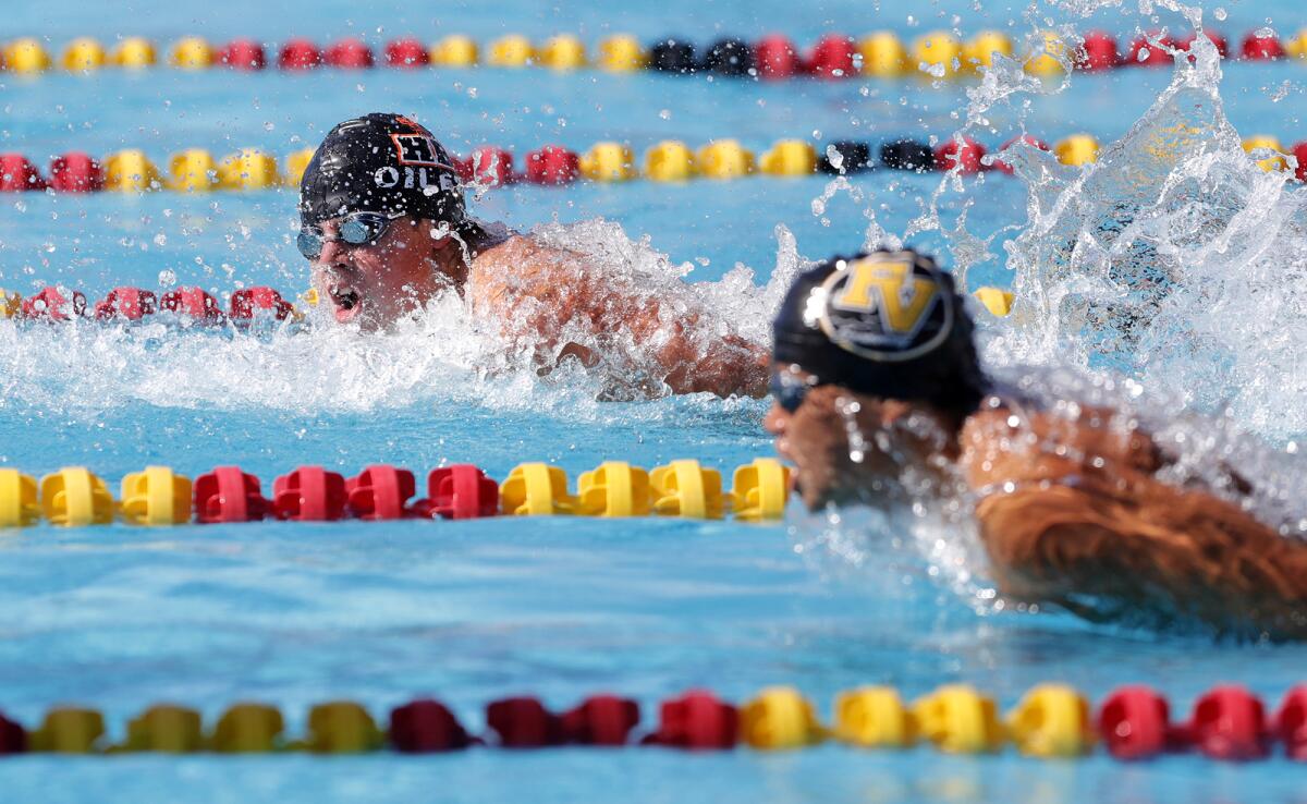 Ryder Dodd of Huntington Beach and Fountain Valley's Ivan Nghi, from left, compete in the boys' 100 butterfly on Friday.